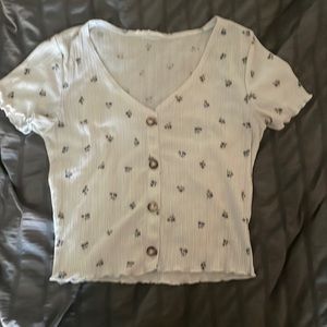 white cropped tee with flowers and buttons down the middle